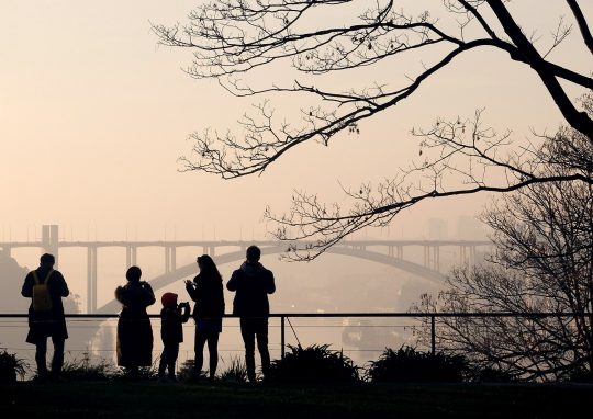 Fotografías de Portugal. Lámina con una con una foto en la que se aprecia una escena urbana de gente (turistas) en un mirador de Oporto con un puente al fondo al atardecer.