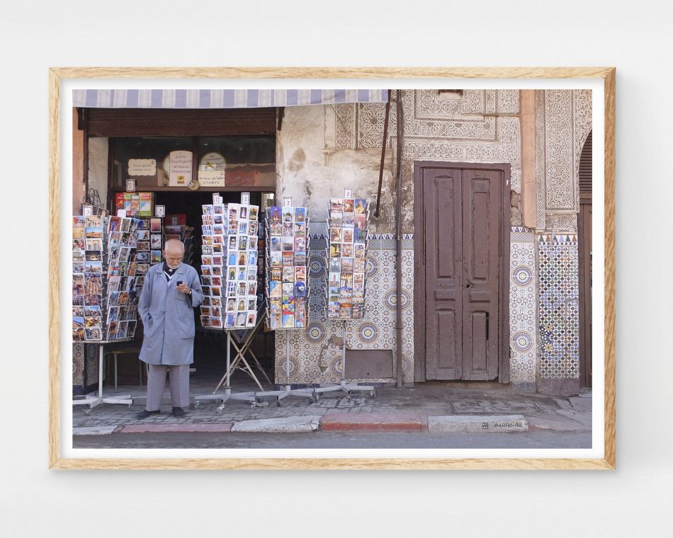 Fotografía costumbrista en color de un hombre vendedor de postales en una calle de Marrakech, Marruecos. Fotos de viajes por el norte de África.