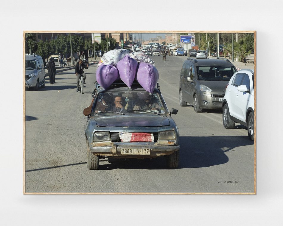 Foto enmarcada en color de un choche muy cargado y viejo en una carretera de marruecos. Venta online