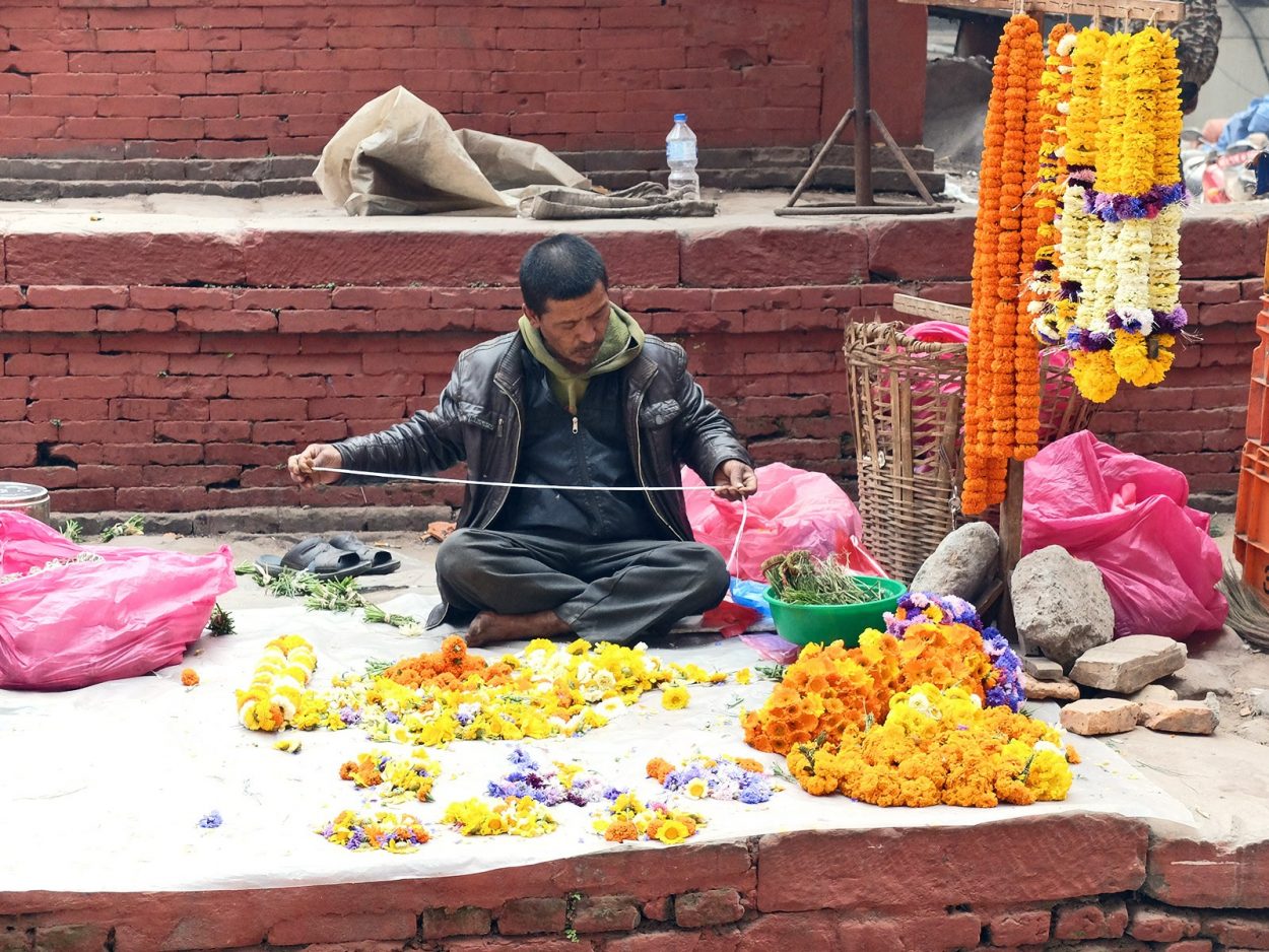 un hombre arreglando flores en kathmandu nepal